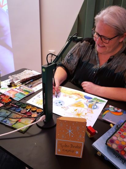 Illustrator Julie Østergaard er i gang med at male til foredrag for børn