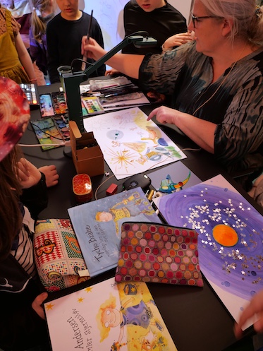 Illustrator Julie Østergaard med børn omkring hendes tegnebord